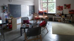 kleiner Raum mit Tisch Sessel Tafel und Lernmaterial